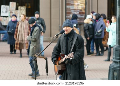 Moscow, Russia - March 8, 2020:   Lifestyle Concept. Middle Aged Street Musician Playing Guitar At The City Street. Crowd Of People Around. Close Up. Frontal View