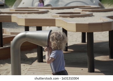 Moscow, Russia, May 07 2019. Little Cute Boy Plays Alone On Playground In Park. Curious Child Stuck His Head In Pipe, Is In Danger Without Adult Supervision.