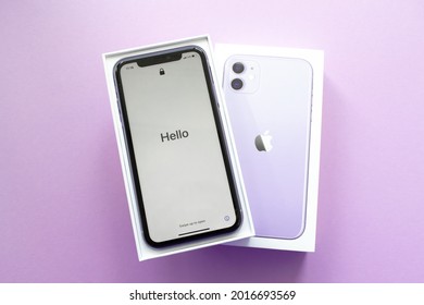 Moscow, Russia, May 2021: A new iPhone 12 model of violet color in an open branded box on a lilac background. On the iPhone screen, welcome in English - Hello!