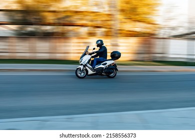 Moscow, Russia - May 2022: Man Riding Motor Scooter Yamaha On The Street, Side View Of Young Biker In Helmet Riding Scooter Along The City Road