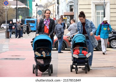 Moscow, Russia - May 2022: Two Women Walking With Baby Prams On City Street. Young Mothers, Leisure At Spring Weather