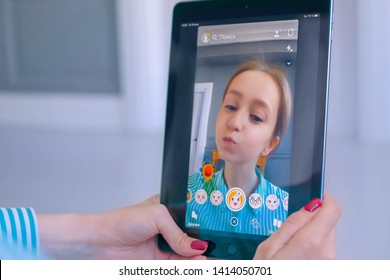 MOSCOW, RUSSIA - MAY 24, 2019: Woman using Snapchat multimedia messaging app with 3d face mask filter on tablet at home. Face detection technology, AR, social media, selfie, entertainment concept