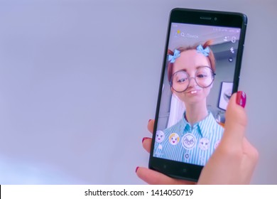 MOSCOW, RUSSIA - MAY 24, 2019: Woman Using Snapchat Multimedia Messaging App With 3d Face Mask Filter On Smartphone At Home. Face Detection Technology, AR, Social Media, Selfie, Entertainment Concept