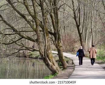 MOSCOW, RUSSIA - May 3, 2022. Two Women Walk Along A Path Under A Large Willow Tree In The Park.