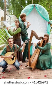 MOSCOW, RUSSIA - MAY 30, 2015: Young Musicians Of Musical Band Polca An Ri Play Music Against Arch Decorated Green And White Fabrics. Polca An Ri Plays Traditional Irish Music.