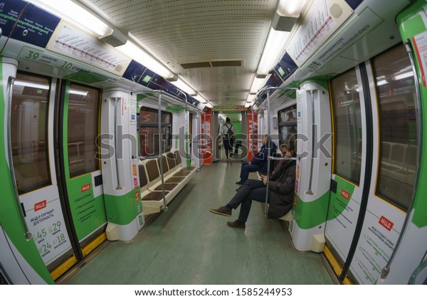 Moscow, Russia - November 20, 2019: Photography\
of people in the carriage of Moscow subway train in night. Somebody\
sitting, using smartphone. Urban transportation, travelling\
culture