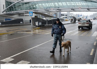MOSCOW, RUSSIA - NOVEMBER 24, 2015:A police inspector-dog handler patrols with a dog the territory of Sheremetyevo international airport in Moscow