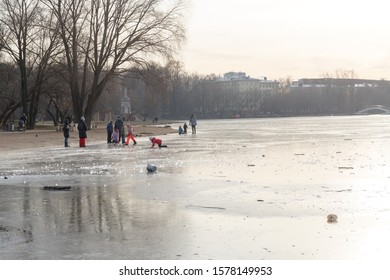 Moscow, Russia, November 24, 2019: The First Thin Ice On The Pond At The Beginning Of Winter In The City Park. Children And Adults Walk On Thin Ice At The Edge Of The Shore