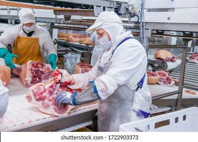 Moscow, Russia. October 17, 2017. Meat Processing Plant. Two Workers Are Busy Cutting Pig Legs.