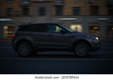 Moscow, Russia - October 2021: Side View Of Brown Range Rover Evoque SUV Driving On The Urban Road. Night Traffic Scene.