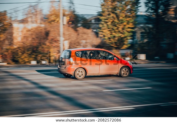Moscow, Russia - October 2021: Very fast driving red\
compact hatchback on the street. Honda Jazz car first generation in\
motion, rear side view