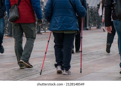 Moscow, Russia, October 23, 2021. An elderly woman walks down the street with Nordic sticks. Healthy lifestyle. Family walk around the city. Rear view. Portrait without a face.