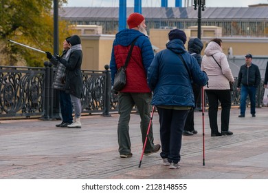 Moscow, Russia, October 23, 2021. Grandma And Grandpa Are Walking Down The Street Of The City With Nordic Sticks. Healthy Lifestyle. Family Walk Around The City. Rear View. People Around.