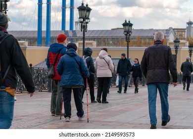Moscow, Russia, October 23, 2021. Grandma and grandpa are walking down the street with Nordic sticks. Healthy lifestyle. Family walk around the city. Rear view. People around.