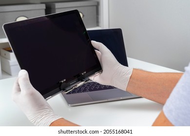 Moscow, Russia, October 3, 2021: A man replaced a broken monitor on a laptop and holds it in his hands in a light white room.