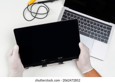 Moscow, Russia, October 3, 2021: A man replaced a broken monitor on a laptop and holds it in his hands in a light white room.