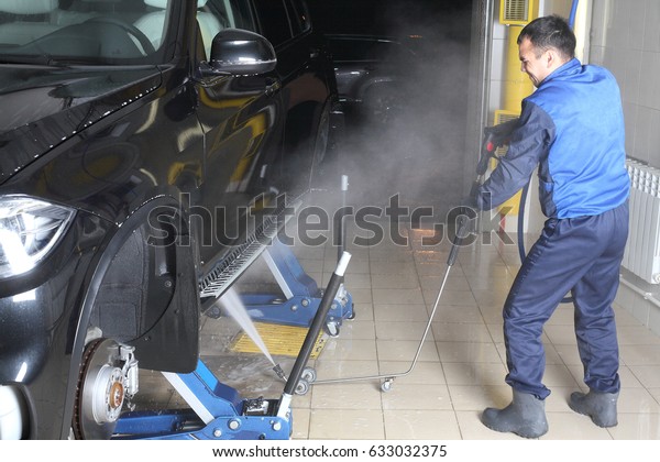 MOSCOW, RUSSIA - OCTOBER 4,\
2015: The worker washing of the car under a high pressure. Car\
service.