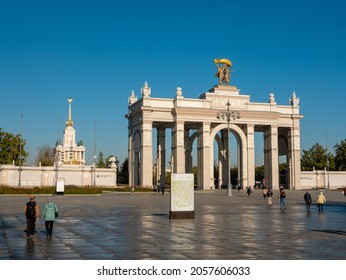 Moscow, Russia - October 5, 2021: Arch of the main entrance of VDNKh. People walk in the square near the entrance to the park.