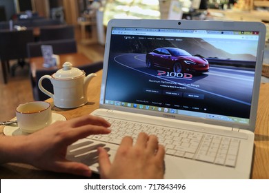 MOSCOW, RUSSIA - SEP 16, 2016: Mans Hands Keyboarding On Laptop Computer In Cafe Room, Tesla Auto Dealer Website On Monitor, Closeup