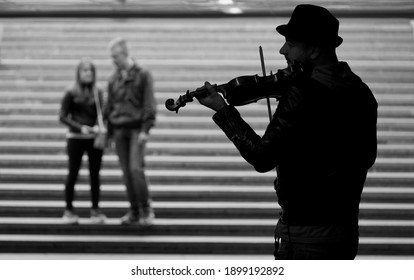 Moscow, Russia - September, 09, 2015: Violinist plays the violin in the underpass next to a couple in love, black and white photo                              