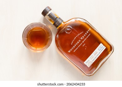 Moscow, Russia - September 22, 2021: Glass And Lying Bottle With Woodford Reserve Straight Bourbon Whiskey On Light Table. Making Fine Bourbon Began On The Site Woodford Reserve Distillery In 1812