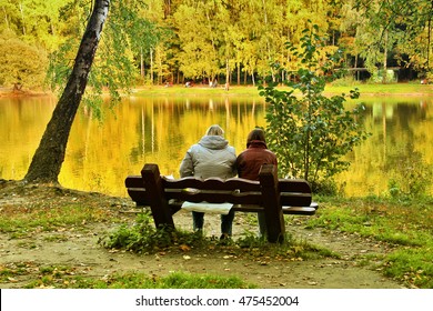 MOSCOW, RUSSIA - SEPTEMBER 28, 2014: Two People Sitting On Bench Near Lake In Autumn Day On September 28, 2014 In Izmailovskiy Park In Moscow, Russia