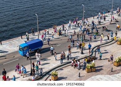 Moscow, Russia - September 6, 2020: People Walk Along The Embankment Of The Khimki Reservoir In The Park Of The Northern River Station. Maintenance Car And Cyclists On The Roadway. Sunny Summer Day.