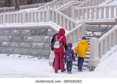 MOSCOW, Russia-8.01.2021: A Family With Children In Bright Overalls Climbs The Stairs On The Territory Of The River Station On A Winter Day. Family Walk And Rest.