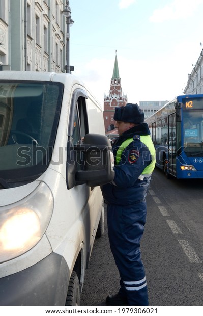 MOSCOW, RUSSIA-FEBRUARY 15,\
2017:The inspector of the road patrol service of the police checks\
the documents of the driver of a stopped car in the center of\
Moscow