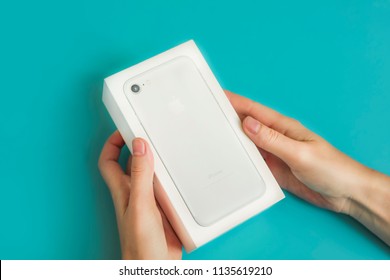 Moscow, Russia-July 14, 2018: Woman Holding A Box Of Apple IPhone Smartphone On A Blue Background. Unboxeind Concept With Copy Space.