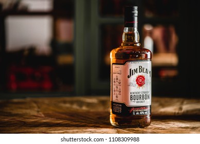 MOSCOW/RUSSIA - APRIL 24, 2018: Jim Beam bourbon bottle on wooden table in dark bar. Jim Beam is a famo?s brand of whiskey and the highest selling American bourbon in the world.