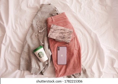 Moscow/Russia - July 23, 2020: Iphone 11 In Purple Shade With Starbucks Coffee Cup And Stylish Bag On Clothes In Bed Closeup. Top View. 