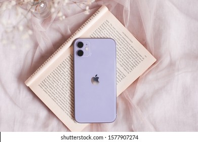 Moscow/Russia - November 22, 2019: Iphone 11 On Open Book With Flowers In Bed Close Up. Modern Technologies. Selective Focus. 