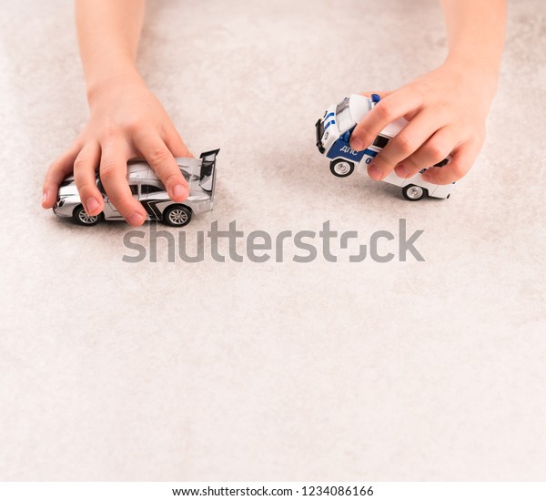 Moscow/Russia-CIRCA 11.2018: a game with car toys,\
Russian police car and a grey colour racing car, a child is\
playing, on a grey table, chasing\
cars