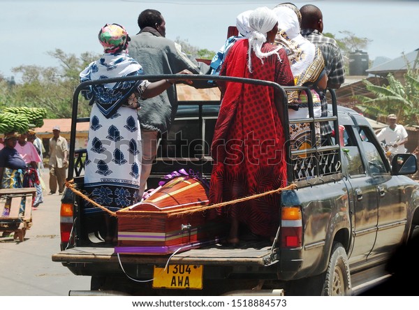 Moshi, Kilimanjaro/Tanzania - 09.30.2015: Funeral\
procession in the village - relatives carry a coffin in an open\
pickup truck\
