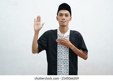 Moslem Asian man looking to the camera with happy face expression while waving his hand to greet others