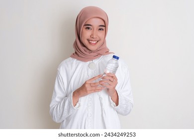 Moslem Asian woman smiling happy while holding a plastic drink bottle - Powered by Shutterstock