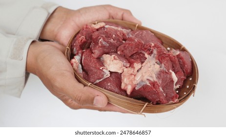 A moslem man is holding raw beef meat on a Wicker bamboo.The feast of Qurban Ied al adha mubarak. - Powered by Shutterstock