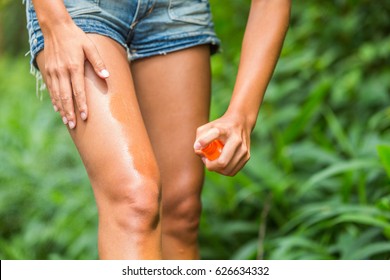 Mosquito Repellent Spray. Woman Spraying Insect Repellent Against Bug Bites, Zika Virus Etc On Legs Skin Outdoor In Nature Forest Using Spray Bottle.