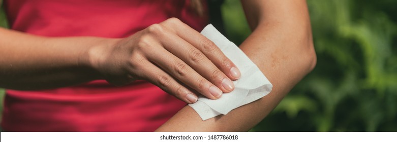 Mosquito repellent woman applying deet wet wipe on arm banner panorama background.