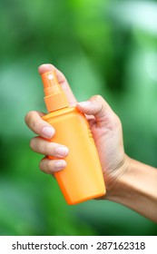 Mosquito repellent. Woman spraying insect repellent for skin outdoor in nature forest using spray bottle.