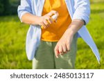 Mosquito repellent. Woman using insect repellent spray outdoors. High quality photo