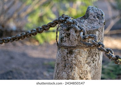 moss covered granite column, rusty iron chain in Latvia country cemetery
