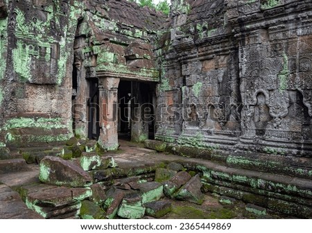 Moss covered green stone temple exterior and bricks at the Ta Prohm Tomb Raider Temple complex wall in Angkor Wat historical park, Seim Reap, Cambodia