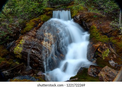 Moss covered rocks split by a mountain spring waterfall in Banff Canada during summertime.