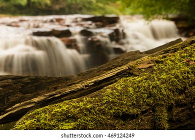Mossy log frames the blurred motion waterfall on Muddy Creek running into Cheat River off Route 26 in Preston County West Virginia