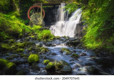 Mossy rocks in stream leading to waterwheel and waterfall in Glenariff Forest Park, Antrim, Northern Ireland. Long exposure and soft focus photography