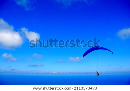 The most beautiful shade of blue. A person paragliding with a magnificent view. Sport and adrenaline.