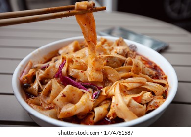 The most famous Chinese dish from Shaanxi province called biang biang noodles alternatively known as youpo chemian served with spicy chily oil chicken and fresh crunchy vegetables  