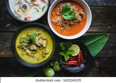 Most famous Thai foods; red curry pork, green curry pork, chicken coconut soup or in Thai names "Panang", "Kaeng Keaw Whan" and Tom Kha Gai. top view on wooden background.